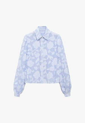 Lyseblå bluse med blomsterprint. Har en spids krave, lange ærmer og et cropped design. Lodrette striber synlige i stoffets struktur.