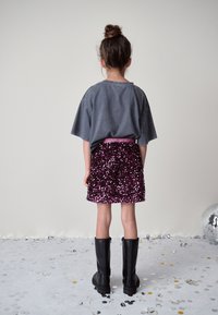 Gray oversized t-shirt, purple sequin skirt, and black knee-high boots. Background features scattered metallic confetti and a disco ball.
