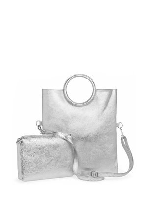 Silberne metallic Tote-Tasche mit kreisförmigem Griff und abnehmbarer kleinerer Tasche. Glatte Textur, minimalistisches Design, verstellbarer Riemen an der kleineren Tasche.
