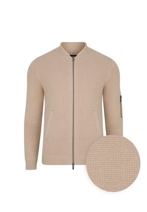 Beżowa dzianinowa kurtka bombowiec z zamkiem z przodu, ściągaczami przy rękawach, dwoma bocznymi kieszeniami i wzorem o fakturze. Zawiera zbliżenie na tkaninę.