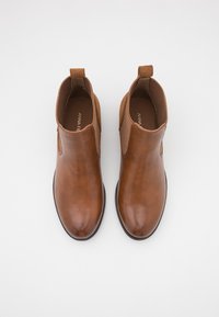 Stivali ankle in pelle marrone con pannelli laterali elasticizzati, texture liscia, linguetta sul retro e design con punta rotonda.
