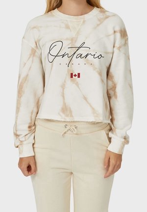Sweatshirt court tie-dye crème avec le texte « Ontario » en noir et un petit drapeau canadien. Il présente des manches longues et un ourlet effiloché.