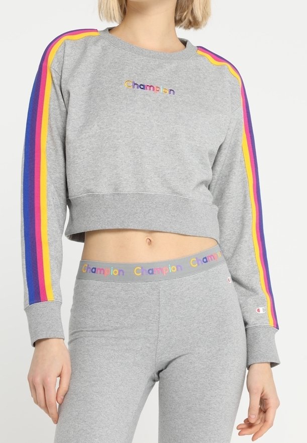 Szara przykrótka bluza z tęczowymi paskami na rękawach i logo "Champion". Zestawiona z dopasowanymi szarymi legginsami z wzorzystym pasem.