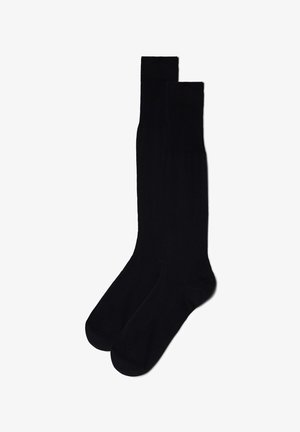 Czarne skarpetki do kolan wykonane z gładkiego materiału, z prążkowanym wzorem u góry i bezszwami w okolicy palców.