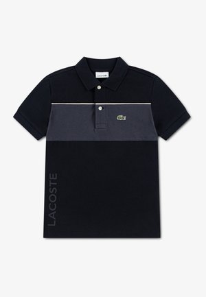 Polo noir et gris à deux tons, avec un col, des boutons et un logo vert. Texte « LACOSTE » en gris sur le côté.