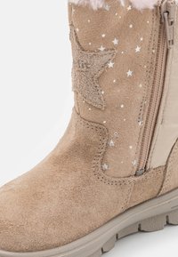 Brune suede ankelstøvler med lynlåslukking, stjernesformede detaljer, sølvfargede stjerne mønstre og teksturert såle for grep. Pelskant på toppen.