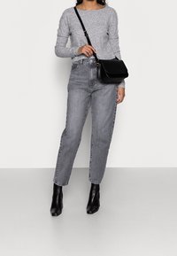 Grå texturerad långärmad topp, högmidjade grå jeans och svarta klackiga ankelboots. Svart axelväska med klaffstängning.