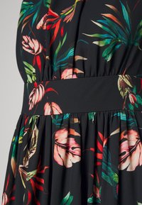 Blumenmusterkleid aus schwarzem Stoff mit bunten tropischen Blättern und Blumen, geraffte Taille und glatte Textur.