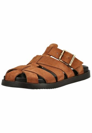 Sandale pour homme en daim marron avec plusieurs brides, semelle noire et boucle dorée ajustable portant la marque "Steve Madden" sur fond blanc.