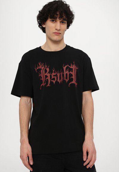 T-shirt en coton noir avec un texte stylisé en flammes rouges. Manches courtes, encolure ronde, coupe décontractée et un détail d'étiquette sur le côté.