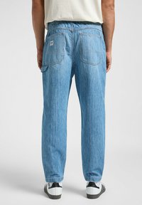 Pantaloni in denim a righe blu chiaro con vita elasticizzata, quattro tasche e orli cuff. Completati con un'etichetta logo sul retro.