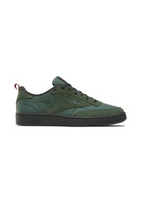Green suede low-top sneakers with black rubber sole, contrasting purple eyelets, and a red heel pull tab. Features textured panels and logo.