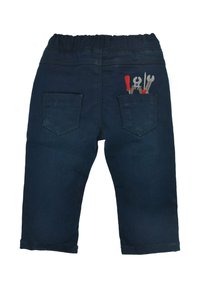 Dunkelblaue Jeanshose mit einem flexiblen Bund und zwei Gesäßtaschen. Eine Tasche hat bestickte Werkzeuge in Rot und Silber.