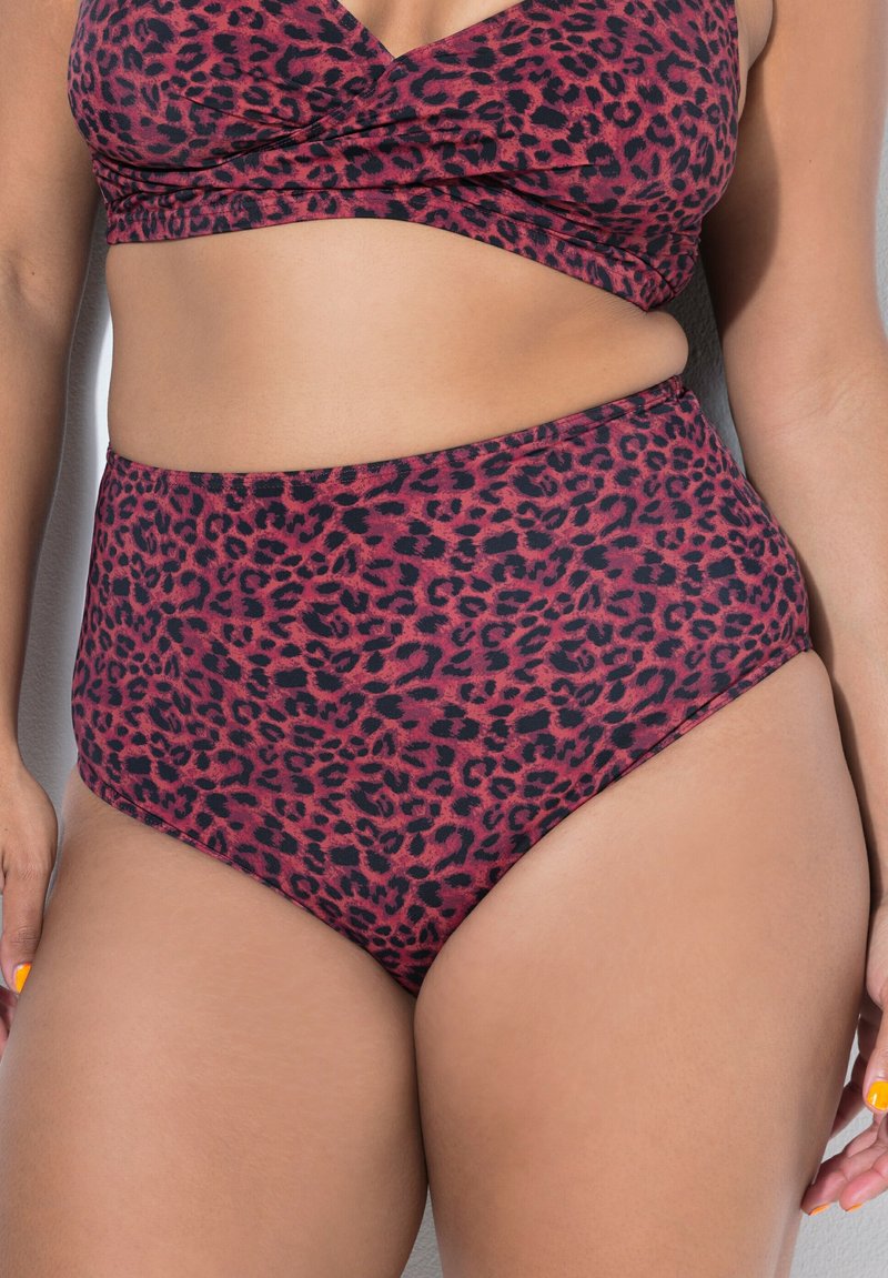 Frau trägt hoch taillierte Bikinihose und passendes Oberteil in Dunkelrot mit schwarzem Leopardenmuster.