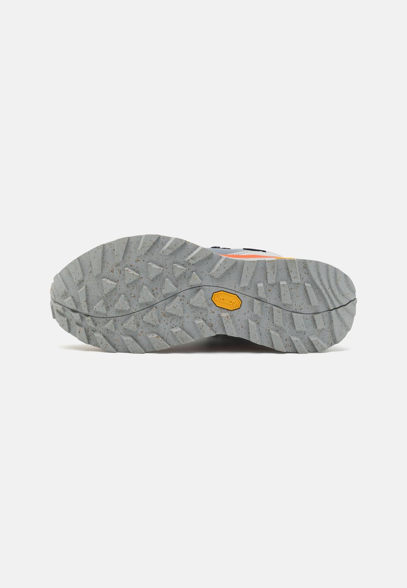 Grau gummi-sohle mit aggressiven, dreieckigen rillen und einem gelben Vibram-logo in der mitte, von unten betrachtet.
