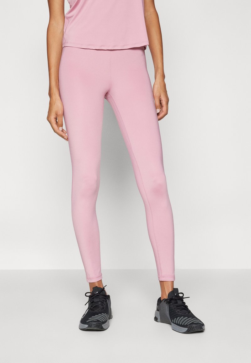 Leggings rosa chiaro realizzati in materiale elastico, caratterizzati da una vestibilità slim e una texture liscia. Indossati con scarpe da ginnastica nere.