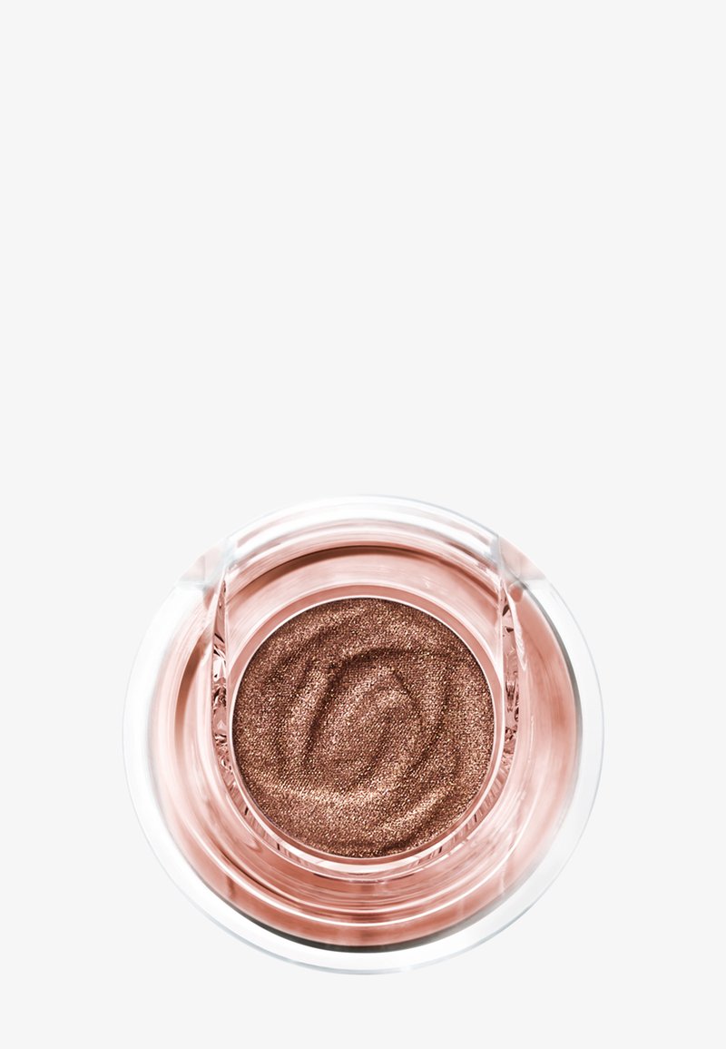 Ombre à paupières crème bronze scintillante dans un récipient rond et transparent avec une texture lisse et tourbillonante à l'intérieur.