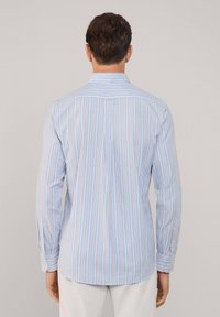 Camisa de hombre de manga larga en azul claro con rayas verticales en rojo y blanco. Presenta un cuello con botones y una pinza en la parte posterior.