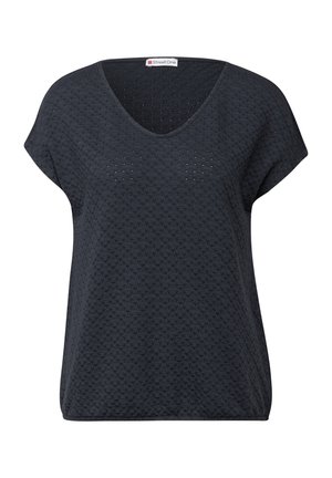 Tummanharmaa lyhythihainen paita, jossa on V-pääntie ja teksturoitu kuvio, jonka koristavat pienet aukot. Valmistettu kevyestä materiaalista, joka istuu löyhästi.