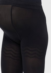 Juodos raištelio legging'ų pagamintos iš permatomo audinio, su tekstūruota bangų raštu apatinėje dalyje ir tvirtu juosmeniu.