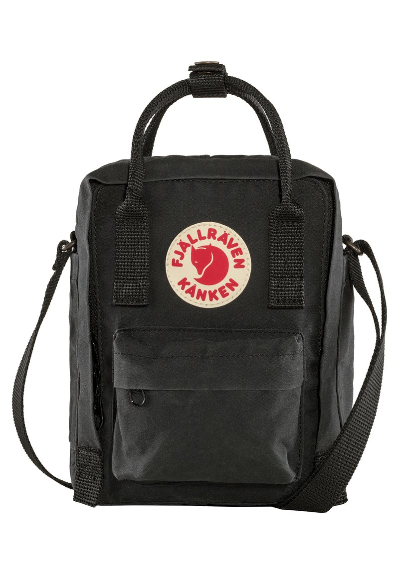 Svart Kånken-ryggsäck med rektangulär form, tygmaterial, framficka med dragkedja och en rund röd logotyp. Har handtag upptill och en justerbar rem.