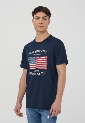 T-shirt in cotone blu navy con una grafica invecchiata della bandiera americana e la scritta "NEW YORK CITY EMPIRE STATE" in bianco. Maniche corte.