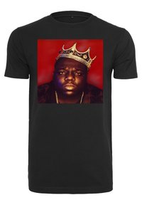 Svart bomulls-T-shirt med ett framträdande motiv föreställande ett porträtt krönt i guld mot en röd bakgrund, vilket framhäver färgkontrast och detaljer.