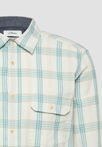 Męska beżowo-niebieska koszula w kratę zapinana na guziki, z kieszenią na piersi i beżowymi guzikami, posiadająca ciemną podszewkę kołnierzyka od wewnątrz.