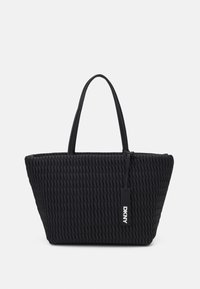 Sac fourre-tout noir en tissu tissé, avec une forme structurée, une surface texturée, des poignées doubles et une étiquette DKNY. Fabriqué à partir de matériaux durables.