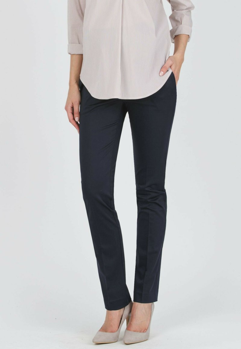 Marineblaue Slim-Fit-Hosen aus einem glatten Stoff, mit einem klassischen Schnitt und klaren Linien, kombiniert mit hellgrauen High Heels.