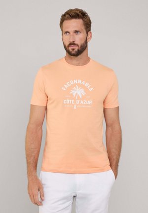 T-shirt en coton orange clair avec un graphique de palmier blanc et le texte "Façonnable Côte D’Azur" dans un design circulaire. Manches courtes.