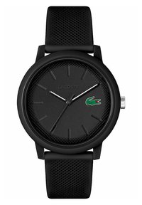 Montre Lacoste noire avec un cadran texturé, aiguilles argentées et accent avec le logo. Bracelet en silicone doux et à motif. Design minimaliste.