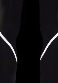 Black athletic leggings featuring a reflective white zigzag design along the side seams. Made from smooth, stretchy fabric for comfort.