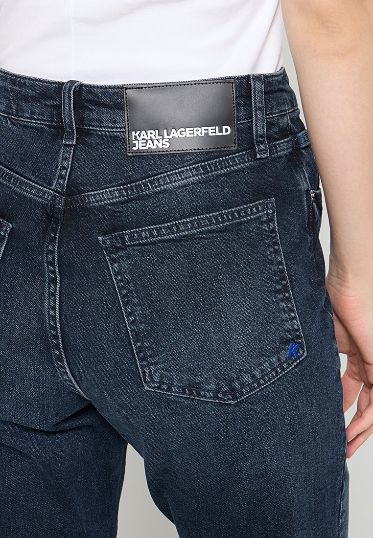 Dunkelblaue Denim-Jeans mit einem Lederetikett mit dem Text "KARL LAGERFELD JEANS", zwei Gesäßtaschen und einem blauen Akzent neben der rechten Tasche.