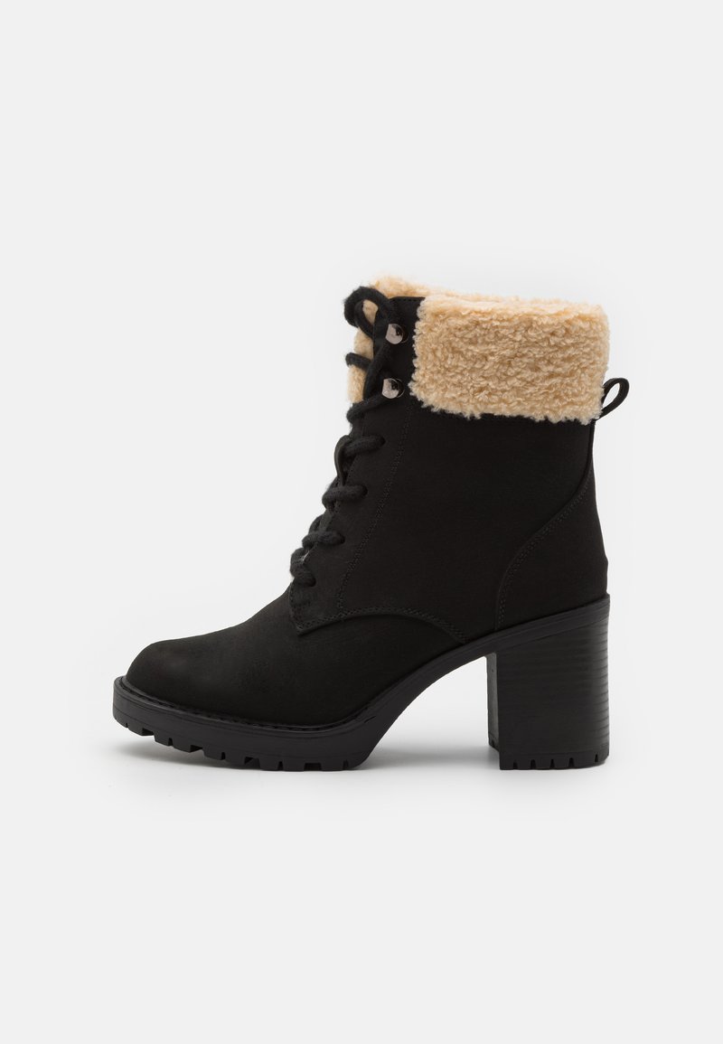 Botine negre din suede, cu un guler căptușit cu blană, toc din plastic, sistem de șirete în față și talpă texturată pentru aderență. Include accente din metal argintiu.