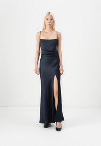 Σατέν βραδινό φόρεμα σε σκούρο ναυτικό χρώμα με λεπτές τιράντες, εφαρμοστό κορσάζ και σκίσιμο στο μηρό στην αριστερή πλευρά. Στρογγυλή λαιμόκοψη κ�αι σχέδιο που φτάνει ως τον αστράγαλο.