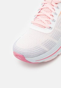 Pantof Sportiv Ușor cu un superior din plasă alb și roz, având un model texturat, vârful întărit și o talpă din cauciuc cu accente roz.