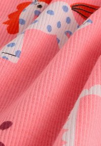 Tissu rose texturé avec un motif animal coloré, des pois et des rayures, affichant des teintes vibrantes de rouge, bleu et blanc.