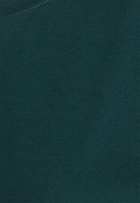 Dark teal cotton fabric with a smooth texture and fine ribbed pattern, featuring a rounded neckline and even stitching detail.