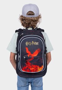 Černý batoh s designem červeného fénixe, textem "Harry Potter" ve zlaté barvě, nastavitelnými popruhy a několika zipovými přihrádkami.