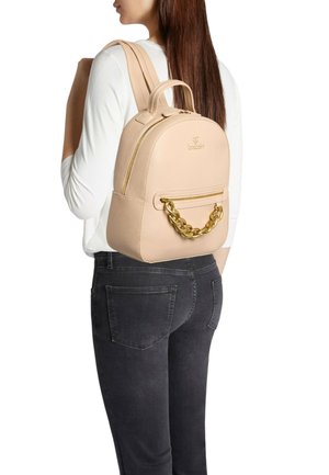 Zaino in pelle rosa chiaro con forma arrotondata, manico superiore e dettaglio a catena dorata sulla tasca frontale. Chiusura con cerniera in alto.