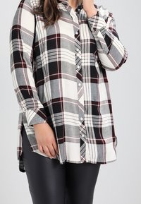 Skjorte med ternet mønster i sort, grå og bordeaux. Blødt stof med lange ærmer og forskudt kant for en afslappet pasform.