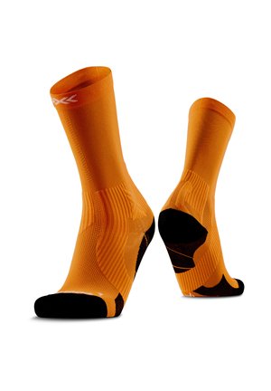 Paar oranje sportsokken met zwarte hiel en teen, geribde boogondersteuning en een klein wit logo vlak bij de bovenste boord.