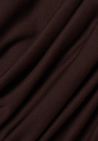 Ciemnobrązowy materiał z miękkimi fałdami i widoczną teksturą tworzącą diagonalne linie na powierzchni.