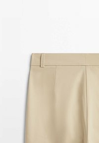 Jupe beige avec passants de ceinture et détail de couture à l'avant, présentée sur un fond blanc uni.