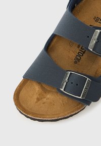 Mornarsko plava kožna sandala s dvije podesive naramenice, srebrnim metalnim kopčama i oblikovanim pluto uloškom za udobnost.