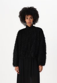 Pulover scurt, negru, pufos, cu mâneci lungi și guler înalt. Fabricat dintr-un material texturat, cu o croială lejeră și un design simplu.