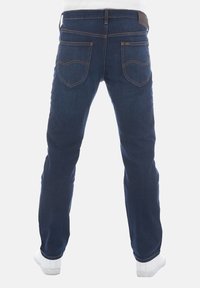 Vaqueros de denim azul oscuro con un corte recto, detalles de costura visibles, dos bolsillos traseros y un parche de cuero marrón en la cintura.