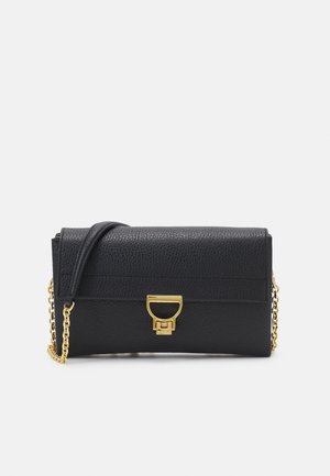 Sac à main en cuir noir avec une finition texturée, quincaillerie dorée et une chaîne en bandoulière. Dispose d'une fermeture à rabat avec un fermoir distinctif.