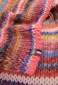 Écharpe tricotée avec des rayures vibrantes dans des teintes de rose, bleu, orange et violet. Comprend une étiquette de marque avec un accent de drapeau français. Tissu doux et texturé.